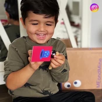 A boy holding up a small red circuit