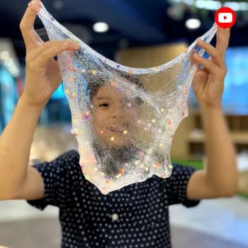 A child holding up a sheet of glittery slime