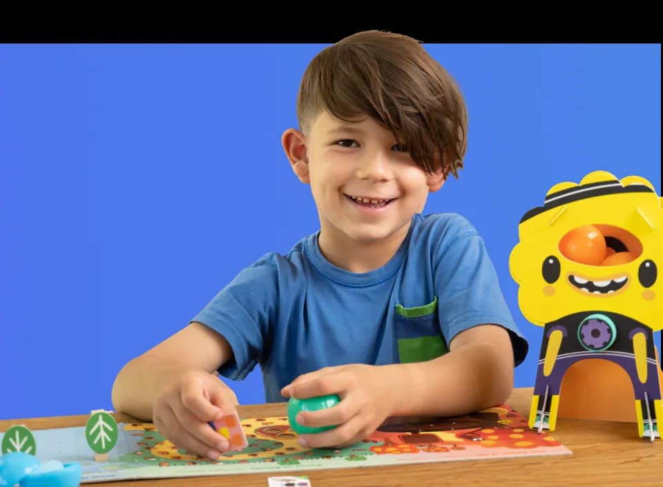 A boy building a MEandMine kit beside a yellow character model