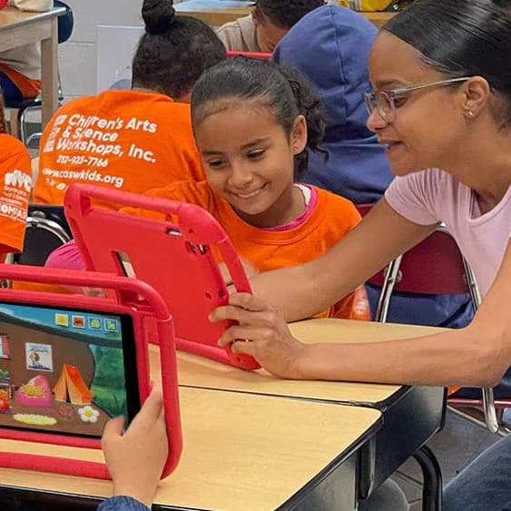 A teacher helping students with red tablets