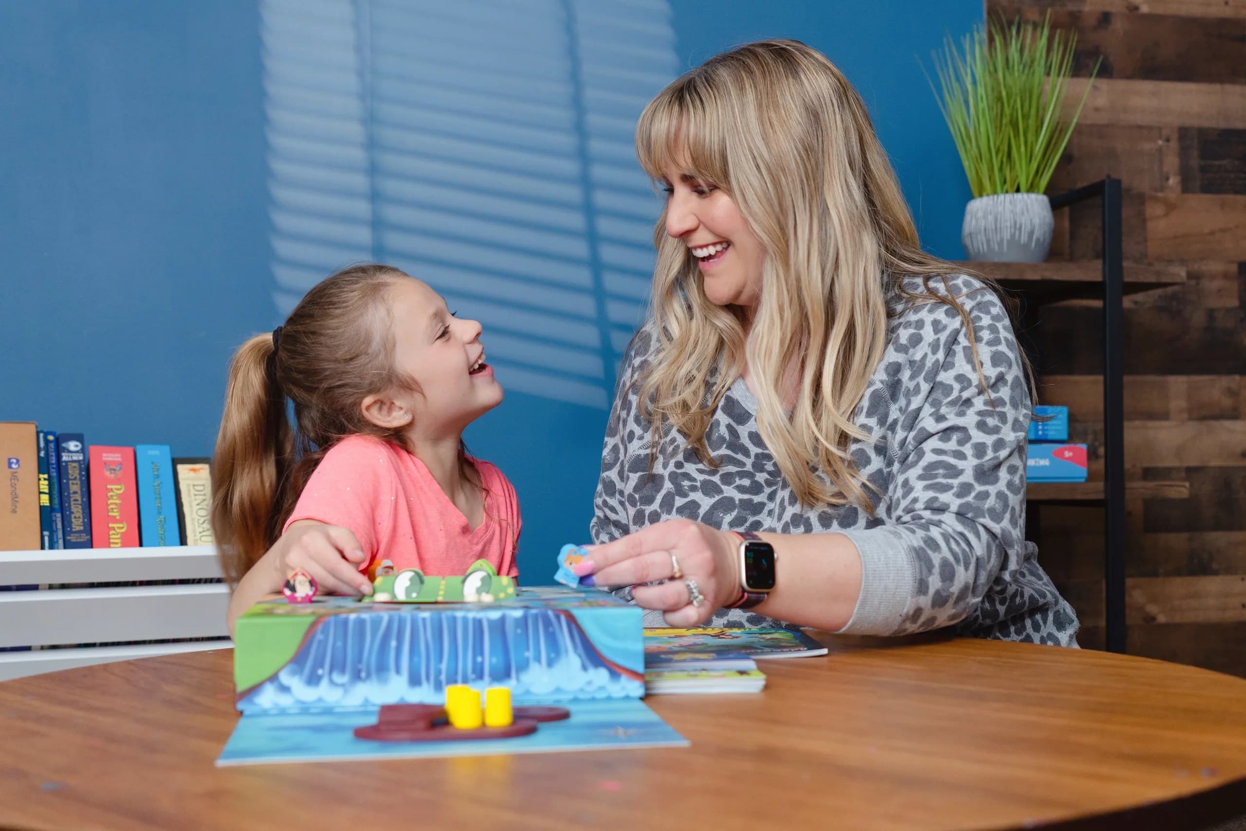 A teacher and a girl laughing over a pop-up book