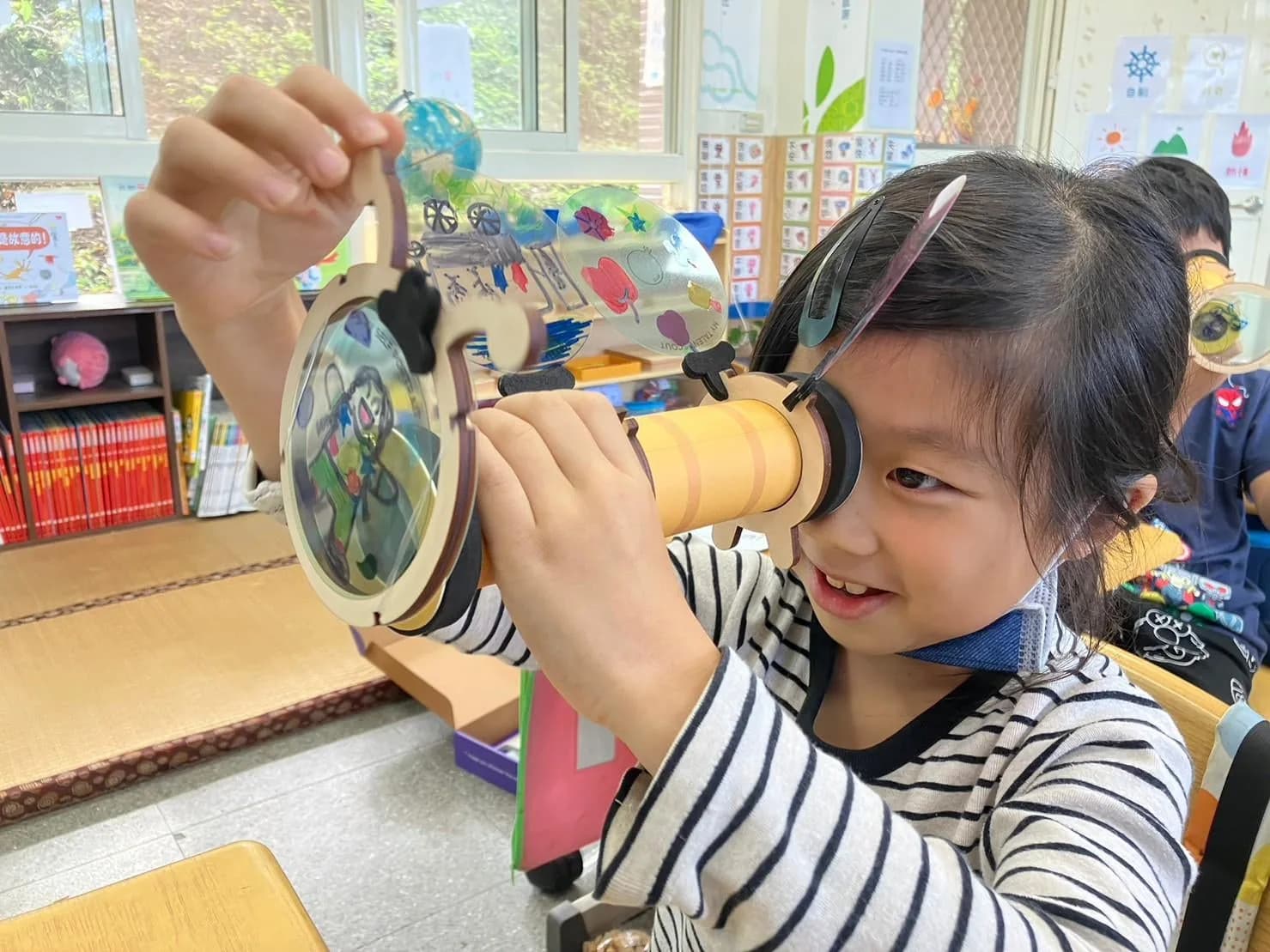 A child looking through a handmade kaleidoscope
