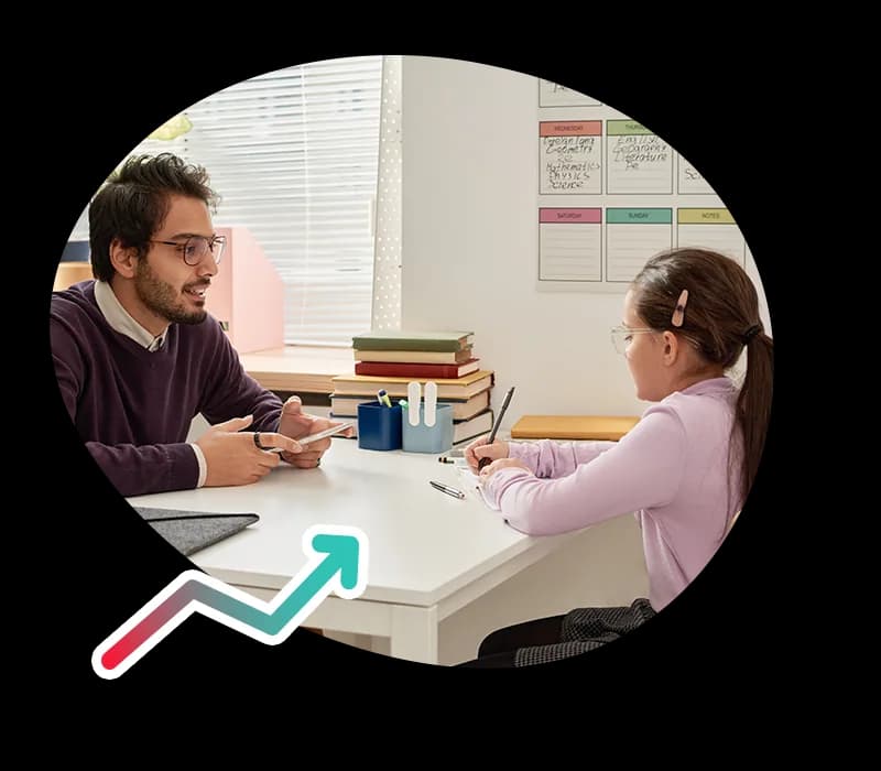 A teacher talking with a student at a desk