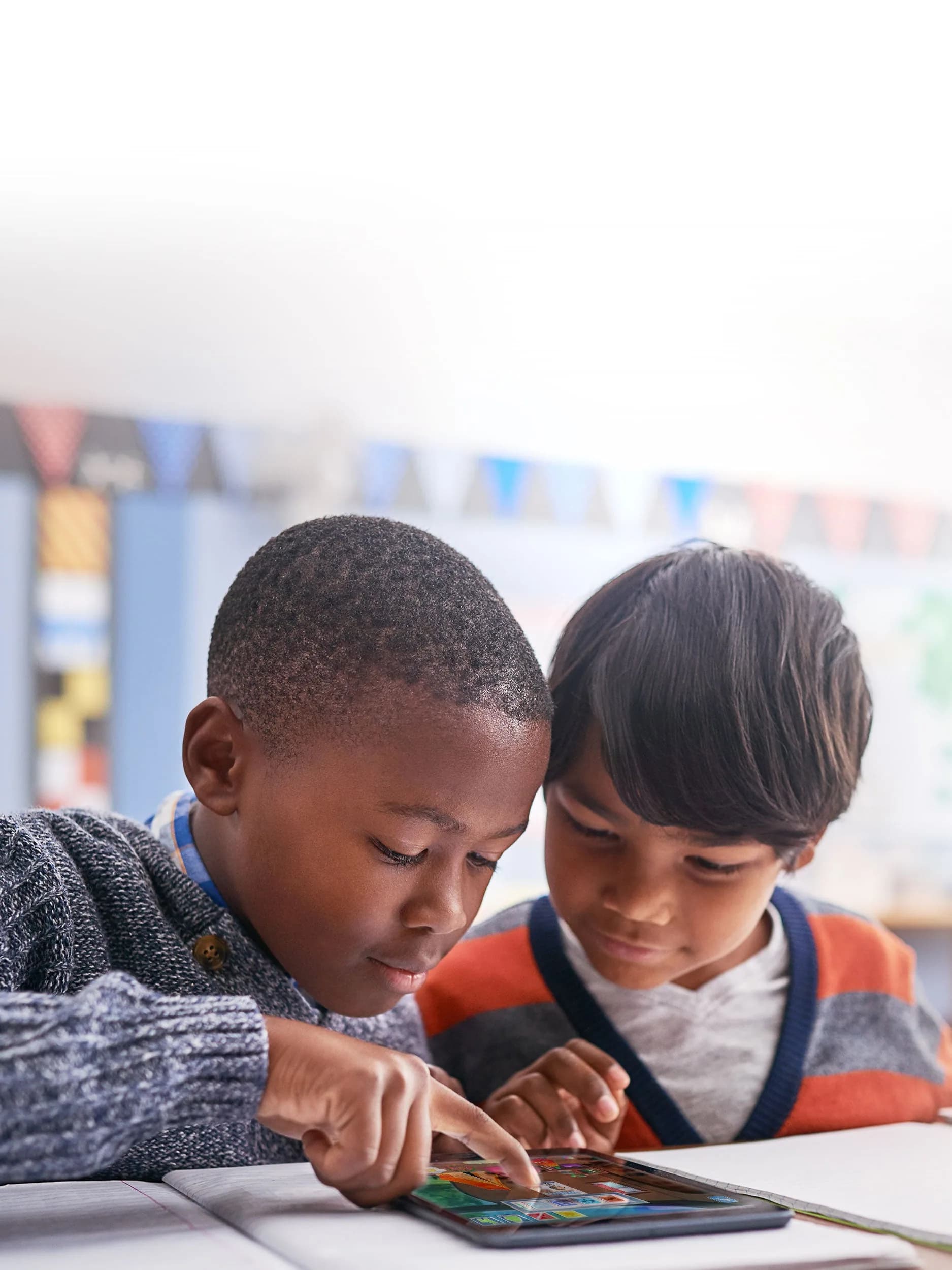 Two boys playing a game on a tablet together