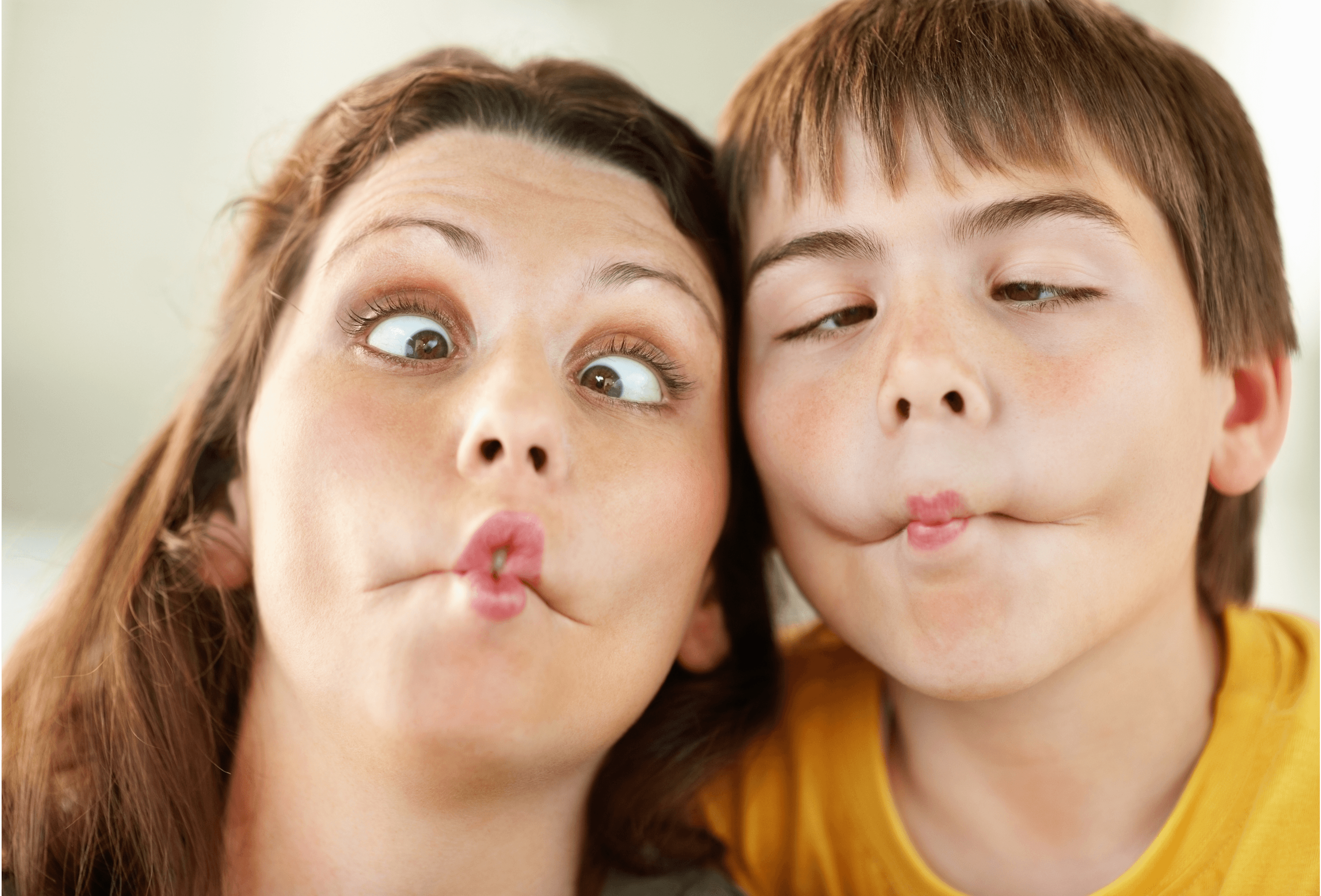 A woman and a boy press their heads together, both making silly fish-lipped faces with crossed eyes.